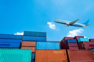 Stacked shipping containers with a cargo plane overhead, representing freight capacity planning for peak season